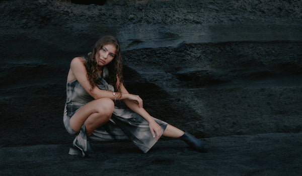 Woman sitting on a dark, rocky surface