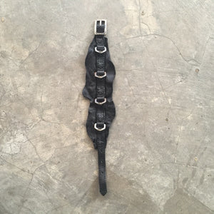 black leather bracelet with metal buckle on a grey background